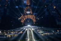 A photograph taken from an helicopter on July 26, 2024 shows an aerial view of the Eiffel Tower and the Olympics Rings lightened up during the opening ceremony of the Paris 2024 Olympic Games in Paris. (Photo by Lionel BONAVENTURE / POOL / AFP)